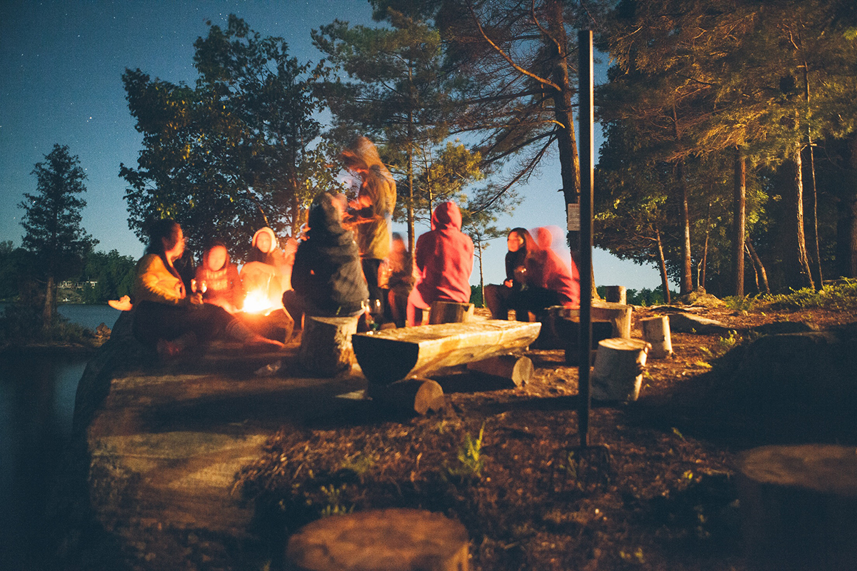 Young people at an outdoor event, around a campfire